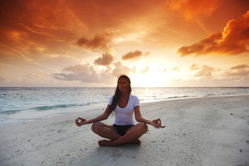 Fototapeta na wymiar Kobieta jogi na plaży o zachodzie słońca