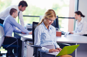 business woman with her staff in background at office