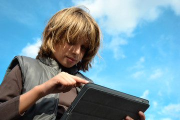 Enfant blond pointant sur tablette numérique