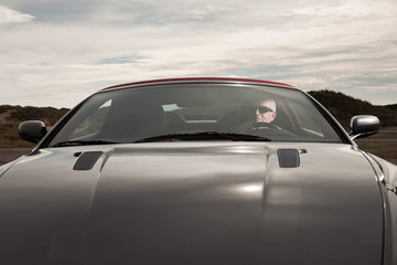 Senior good looking happy retired man driving his sports car