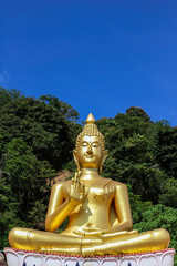 The big golden Buddha statue on hill with blue sky background