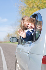 Happy girl waving from a car