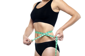 Fit woman measuring her waist, cropped image