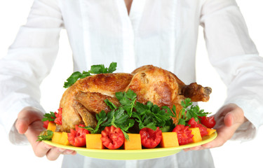 Chef holding a plate of baked chicken with vegetables close-up