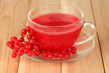 glass cup with broth viburnum on wooden background close-up