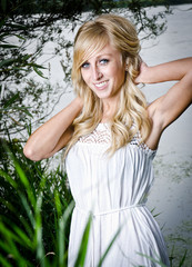 hübsche blonde Frau in der Natur in einem weißen Kleid