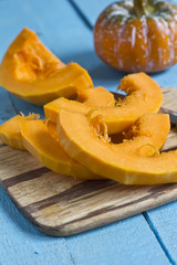 Fresh uncooked cutted pumpkin on board on wooden table. Selectiv