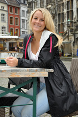 Fototapeta na wymiar Junge Frau sitzt in Straßencafé