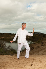 Senior spiritual man dressed in white. Exercising outdoors.