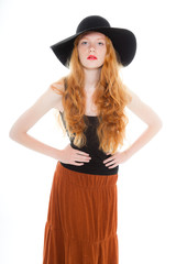 Fashion shot of pretty girl with long red hair wearing a hat.