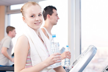 Man and woman drinking water after sports in gym
