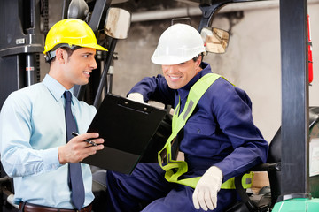 Supervisor Showing Clipboard To Forklift Driver