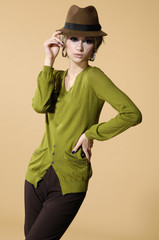 young girl in a hat posing on beige background