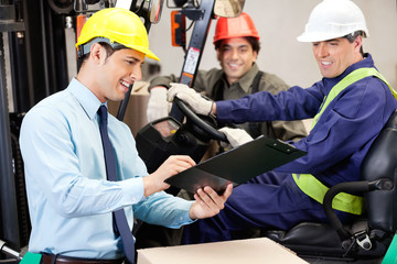 Male Supervisor Communicating With Forklift Driver And Foreman