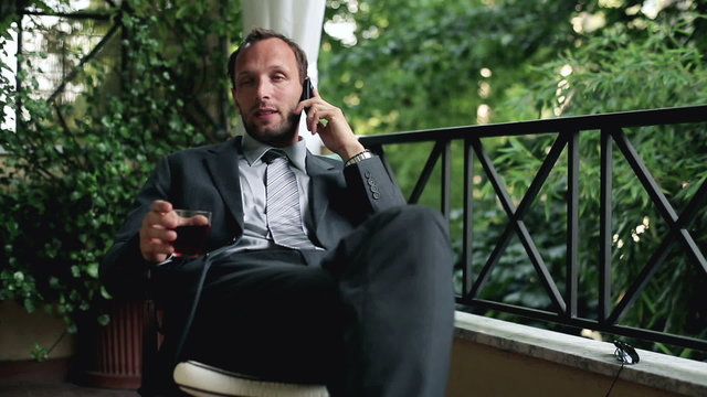 Young businessman with cellphone , drinking whisky