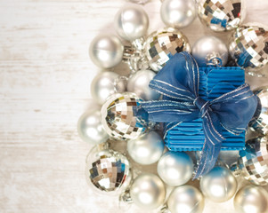 Top view of blue giftbox surrounded by silver baubles