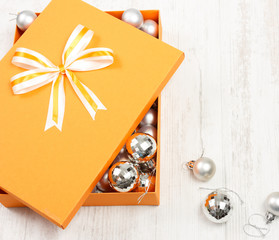 Fototapeta na wymiar Orange Christmas gift box filled with silver baubles