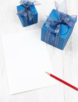 Carton with red pencil in front of  blue gift boxes