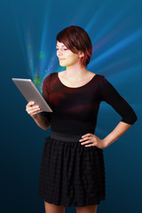 Young woman looking at modern tablet with abstract lights