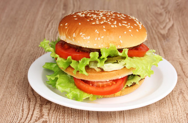 Big and tasty hamburger on plate on wooden table
