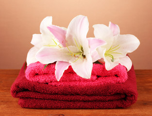 Obraz na płótnie Canvas stos ręczniki z różowego lily na brązowym tle