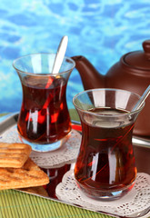 glass of Turkish tea and kettle on color background