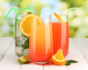 Three cocktails on wooden table on bright background