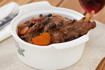 rabbit stew in the white bowl with glass of wine