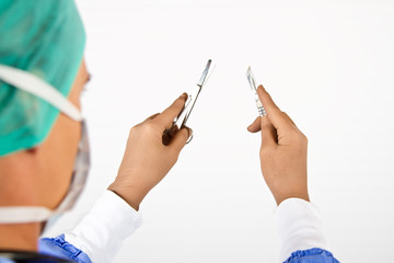 Surgeon holding scalpel and scissors in hand