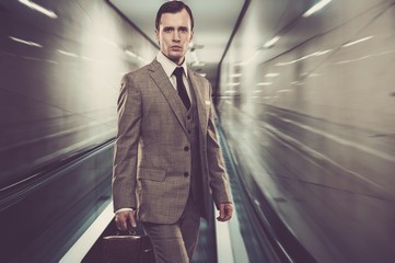 Man in classic grey suit with briefcase standing on escalator