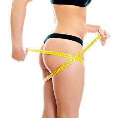 Slim female body with measure tape around hips.