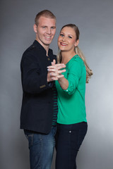 Young couple together in love against grey wall. Studio shot.