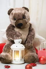 Christmas teddy bear sitting with lantern and gifts around