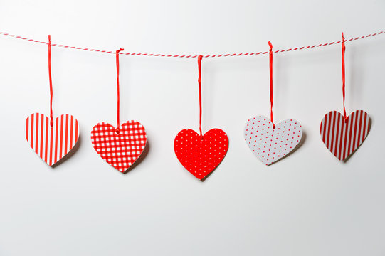 Red textured hearts hanging on white background