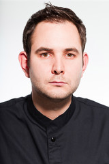 Obraz premium Young male cook with black cooks jacket isolated on white.