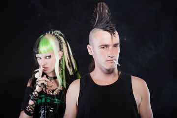 Couple of cyber punk girl punk rock man smoking a cigarette.
