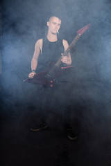 Punk rock man with mohawk playing electric guitar against black.