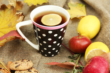 cup of hot tea and autumn leaves, on burlap background