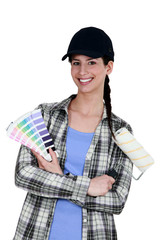 female painter holding a roller brush and a color chart
