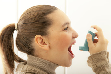 Cute young female start using an asthma inhaler