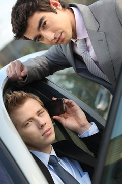 businessmen sitting in a car and talking on a phone