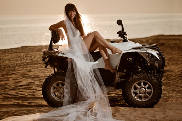 Bride sitting on a quad bike on the beach