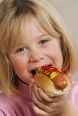 Pequeña niña comiendo perro caliente,hotdog.