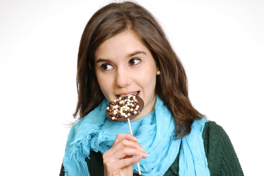 Joven muchacha comiendo una chupeta de chocolate.