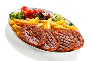 Grilled steaks, French fries and vegetables