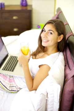 Happy woman smiling working in bed with computer