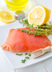 Raw salmon on the white plate with thyme and salt