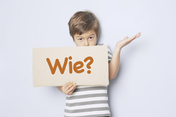 Kind fragt mit Pappschild „Wie?