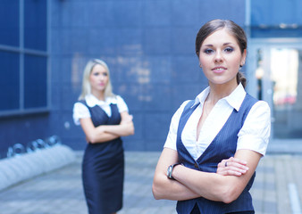 A brunette businesswoman standing in front of her colleague