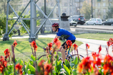 Man in a blue uniform on the racing bike near Canna flowers